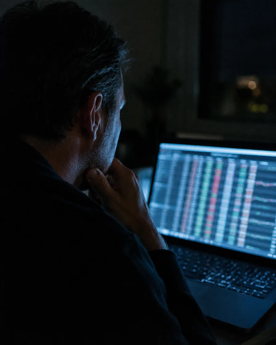 A man at home at night reading a live statistics table on his laptop